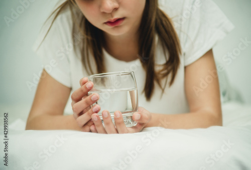 teenage girl with a glass of water on the bed close-up