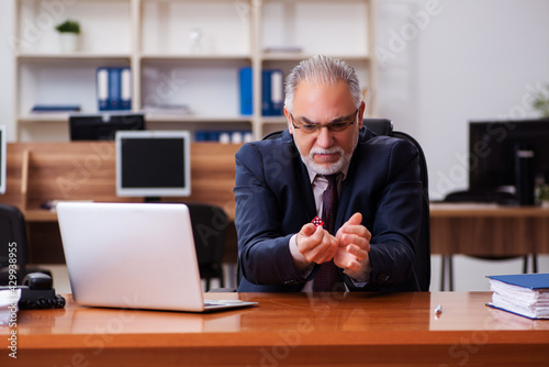 Old male employee in gambling concept at workplace