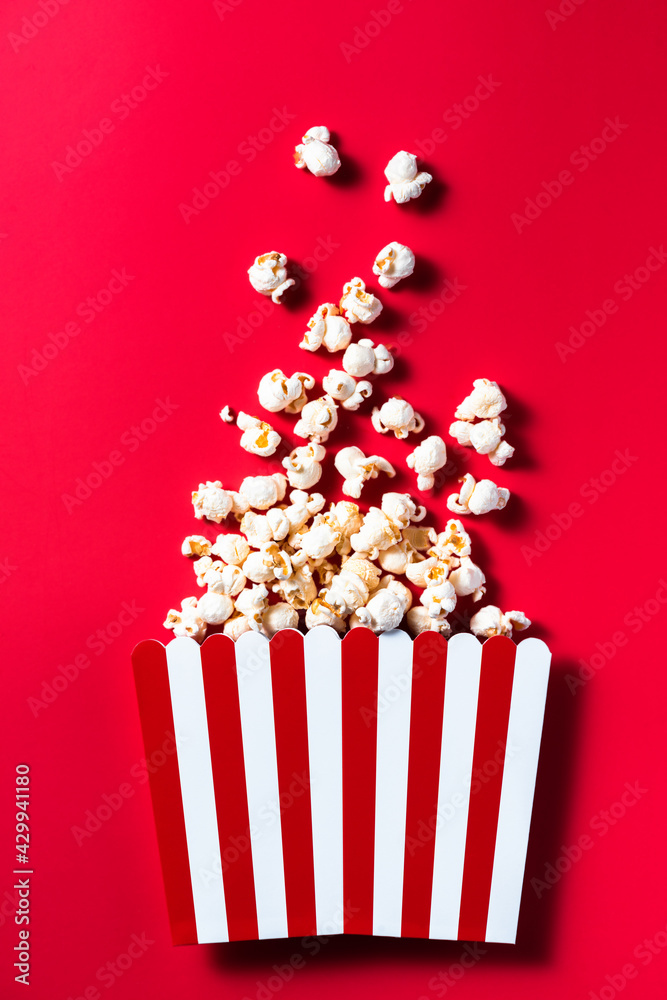 Striped Popcorn Bucket Box on Red Cinemab Background. Movies and Entertainment Concept. Flat Lay .