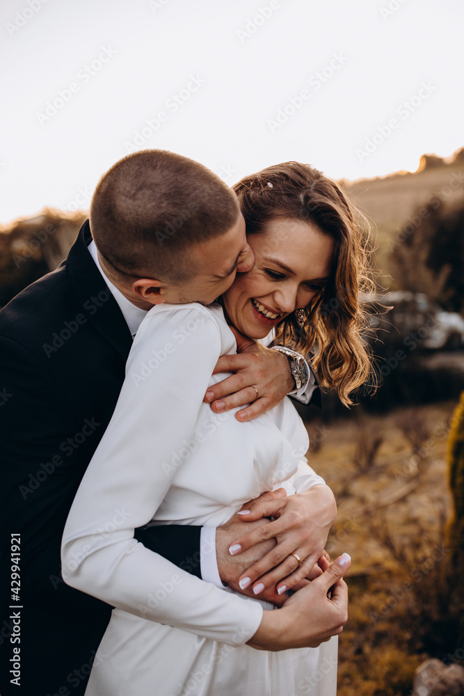 Evening walk of the newlyweds in the garden. Portrait of the bride and groom. Photoshoot at sunset.
