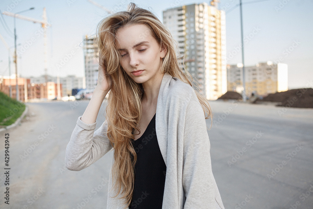 caucasian skinny female with closed eyes outdoors in front of construction site