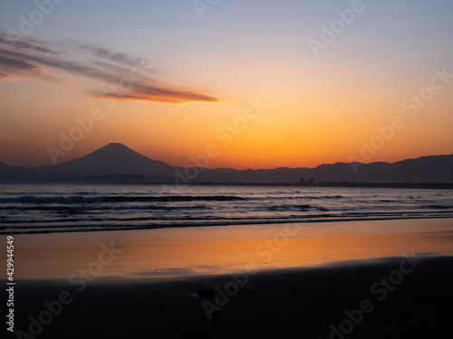 夕日に照らされる海岸と遠くに見える富士山