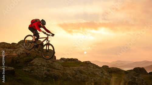 Fototapeta Naklejka Na Ścianę i Meble -  Cyclist in Red Riding Bike on the Summer Rocky Trail at Sunset. Extreme Sport and Enduro Biking Concept.