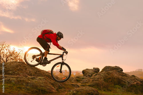 Cyclist in Red Riding Bike on the Summer Rocky Trail at Sunset. Extreme Sport and Enduro Biking Concept.