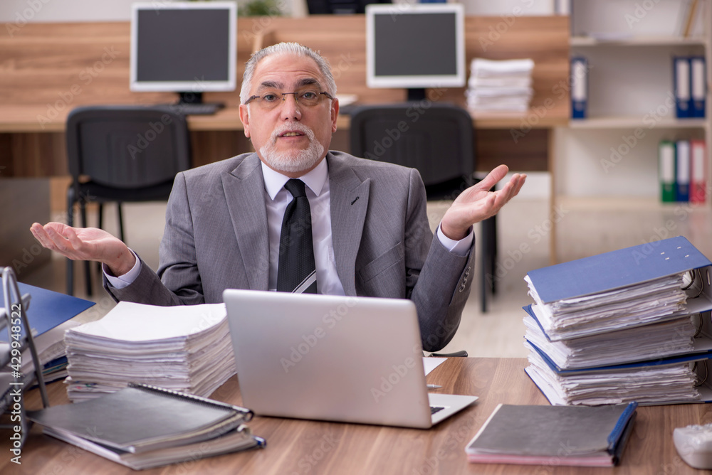 Old male employee unhappy with excessive work in the office Old male employee unhappy with excessive work in the office