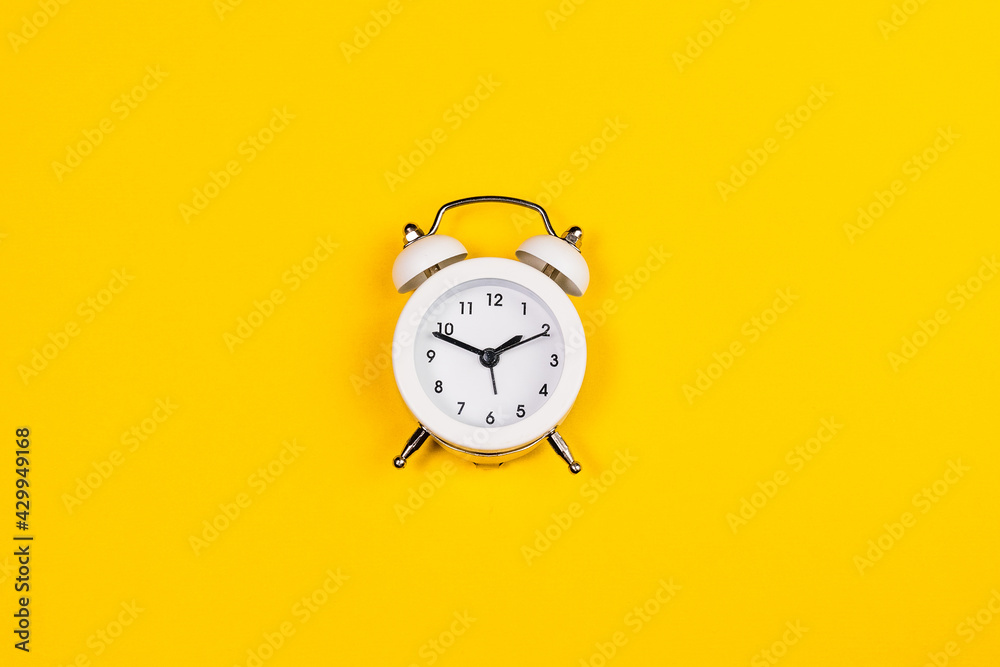 white alarm clock on yellow background. copy space. flat lay white alarm clock on yellow background. copy space. flat lay