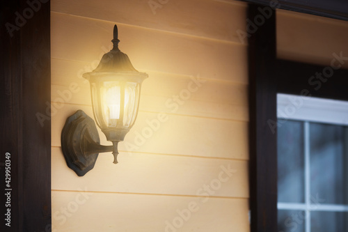 Metal vintage street lamp on the house wall is shining