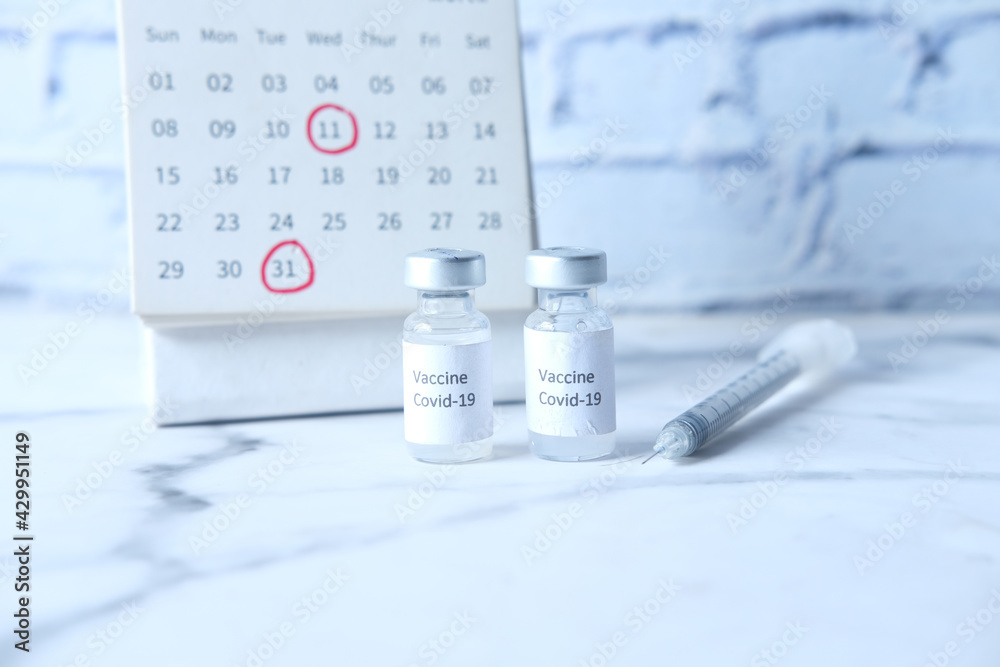 coronavirus vaccine, syringe and calendar on table 