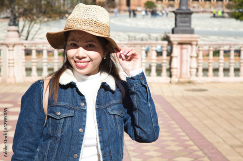 Young and beautiful asian tourist happy holding her hat on a sunny day during her vacation trip