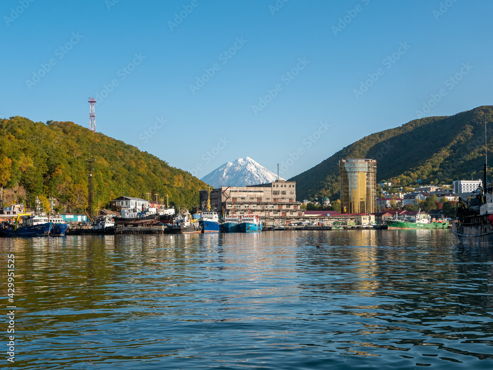 The seaport in the Avacha Bay of Petropavlovsk-Kamchatsky. View from the sailing yacht to the volcano, autumn hills against the blue sky. Kamchatka Peninsula, Russia.