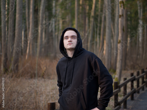 A guy in a black tracksuit, a portrait on a forest background, the sun at sunset, the guy goes in for sports, the concept of a healthy lifestyle