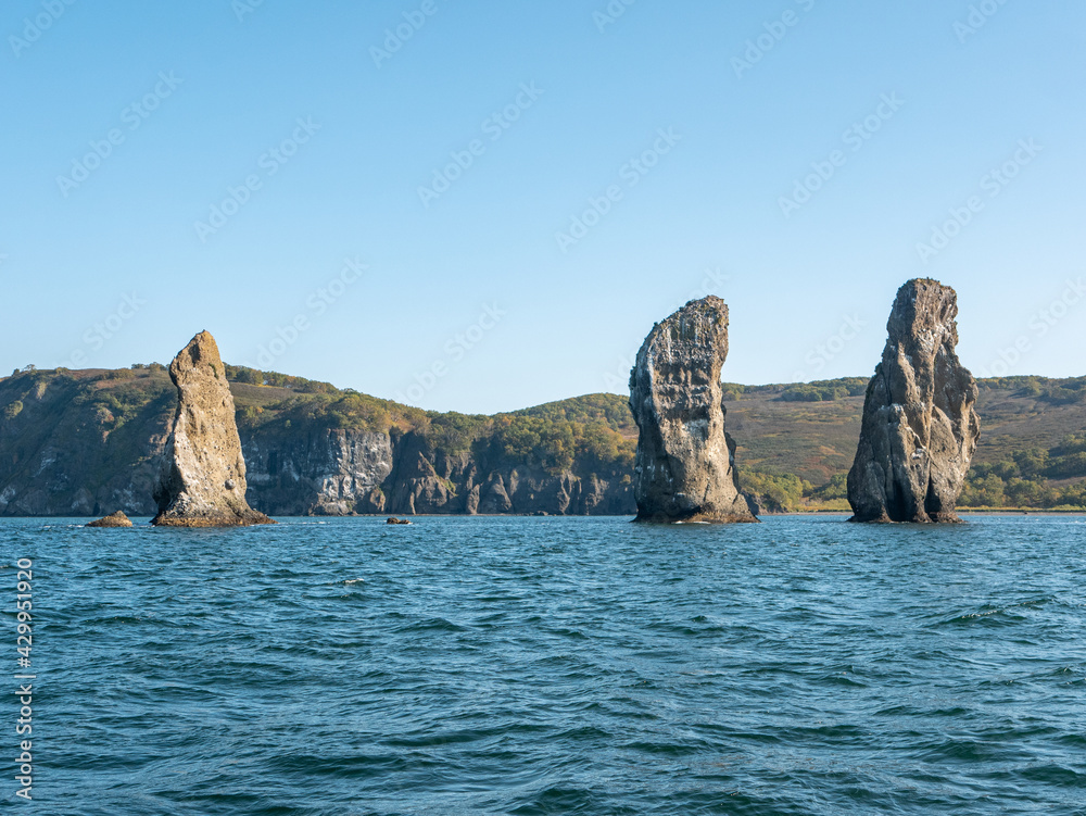 Exit on a yacht to the Avacha Bay of the Pacific Ocean. View of the rocks three brothers are a symbol of Avacha Bay and the city of Petropavlovsk-Kamchatsky. Kamchatka Peninsula, Russia.