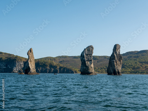 Exit on a yacht to the Avacha Bay of the Pacific Ocean. View of the rocks three brothers are a symbol of Avacha Bay and the city of Petropavlovsk-Kamchatsky. Kamchatka Peninsula, Russia.