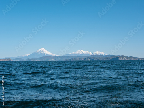 Exit on a yacht to the Avacha Bay of the Pacific Ocean. View from the sailing yacht to the seaport  volcanoes  autumn hills against the blue sky. Kamchatka Peninsula  Russia.