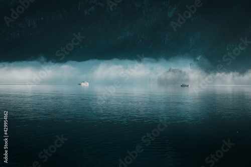 Early morning lake view with fog and mist over the water surface with cute small boats on the lake. Foggy morning lake view in Austria. Hallstatt lake in Austria, Europe