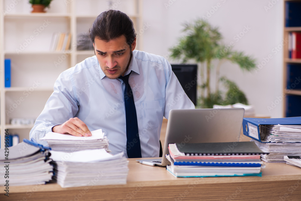 Young male employee and too much work in the office Young male employee and too much work in the office