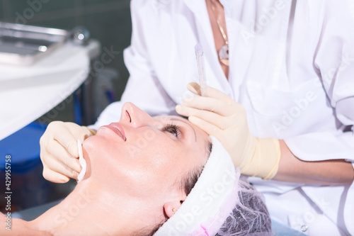 Mature woman having jet peeling facial therapy treatment in beauty clinic