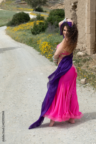 Woman performing belly oriental dancing wearing coloured costume. Dancing outdoors