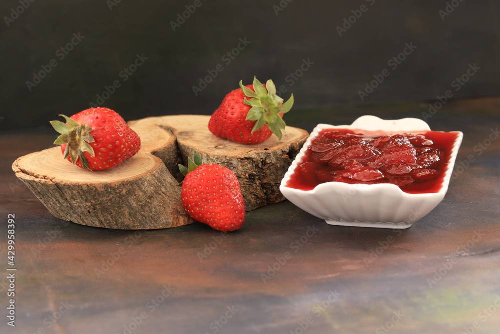 Strawberry jam and strawberries made of natural strawberries in a white bowl.