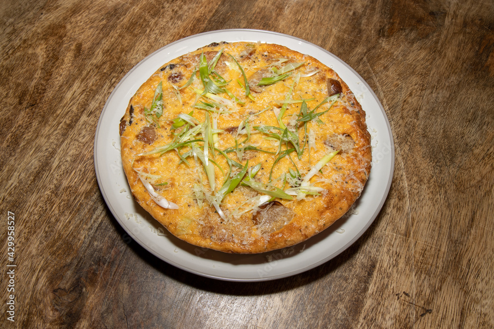 A delicious cooked Sausage and Hash Brown Frittata on a wooden kitchen table A delicious cooked Sausage and Hash Brown Frittata on a wooden kitchen table