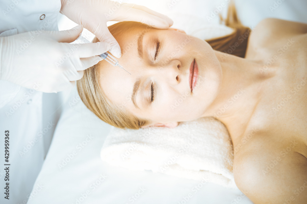 Beautician doctor doing beauty procedure with syringe to caucasian woman. Cosmetic medicine and surgery, beauty injections concept Beautician doctor doing beauty procedure with syringe to caucasian woman. Cosmetic medicine and surgery, beauty injections concept