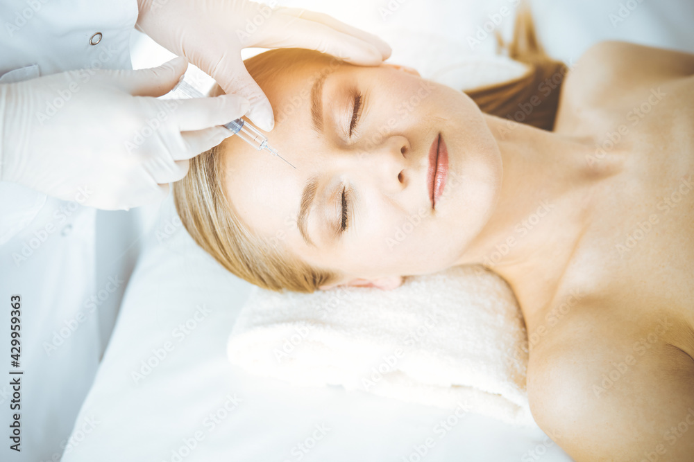 Beautician doctor doing beauty procedure with syringe to caucasian woman. Cosmetic medicine and surgery, beauty injections concept