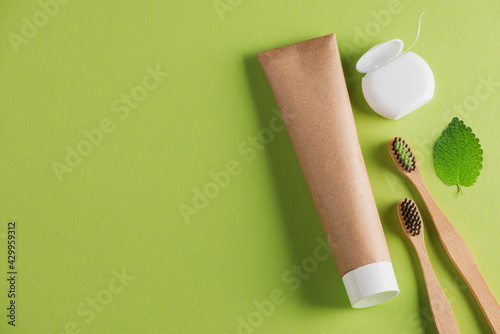 Wooden toothbrushes, organic toothpaste, dental floss and a leaf on green photo