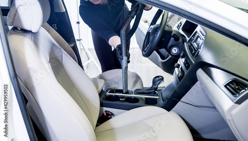 Worker cleans car interior with vacuum cleaner