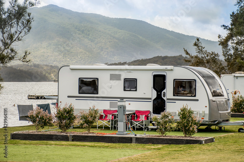 RV caravan camping at the caravan park on the lake with mountains on the horizon. Camping vacation travel concept