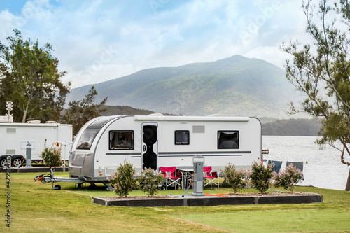 Slika na platnu RV caravan camping at the caravan park on the lake with mountains on the horizon