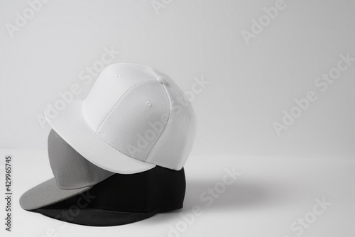 Closeup shot of three blank monochrome white, gray and black baseball cap isolated over light background photo