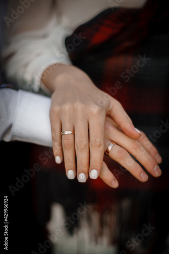 The hands of the newlyweds with gold wedding rings. One on top of the other.