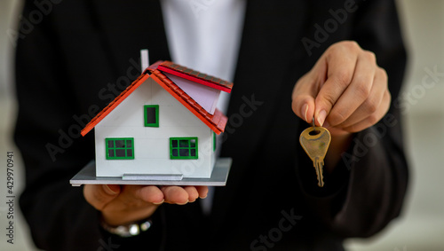 Real estate agents hold home keys for customers. Ideas for real estate, moving houses or renting real estate.Business women catch the key.For home trading.There is space for entering text.