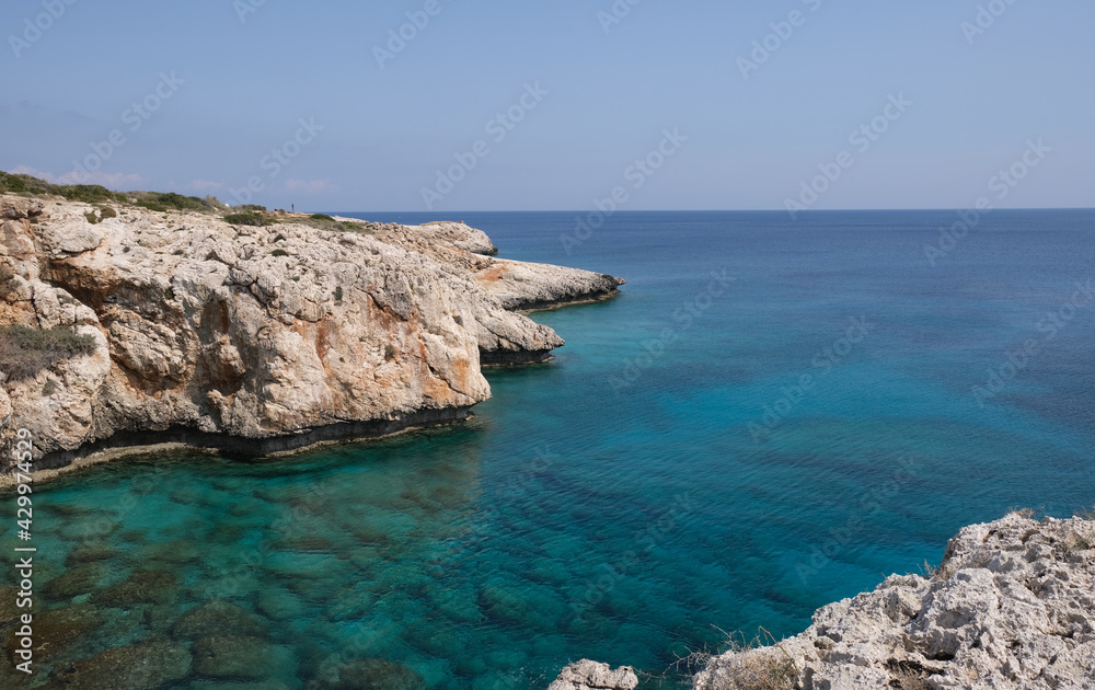 Rocky coastline with blue water and sky.