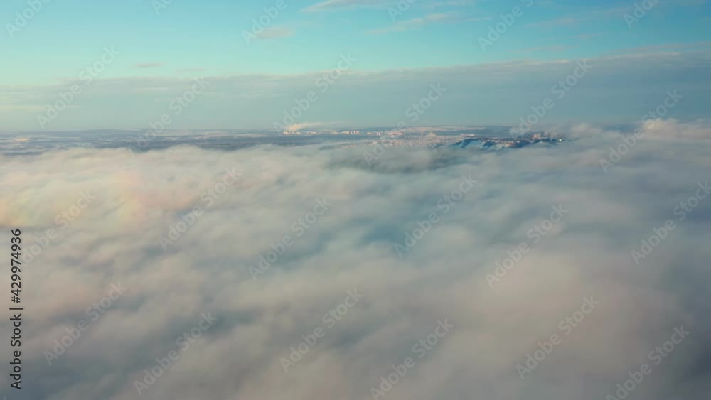 The plane flies through a cluster of golden clouds across the blue sky. The fluffy, snow-white clouds. Spectacular view from the window of an airplane. High quality. 4k footage.