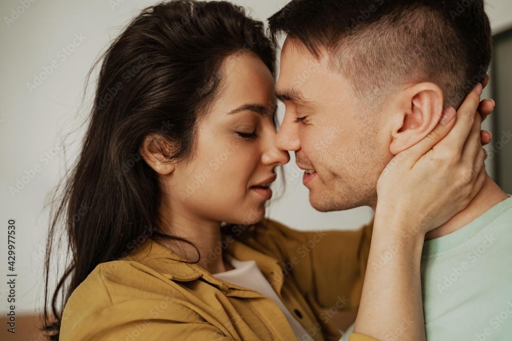 Happy young couple is kissing with passion and love, close up. Young family moving to new apartment