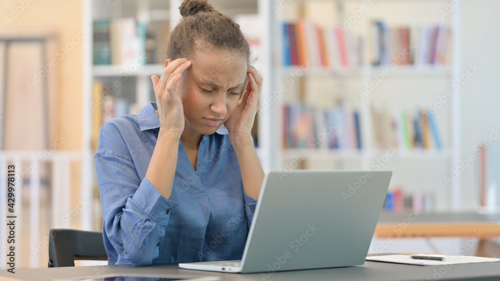 Stressed African Woman with Laptop having Headache in Library Stressed African Woman with Laptop having Headache in Library