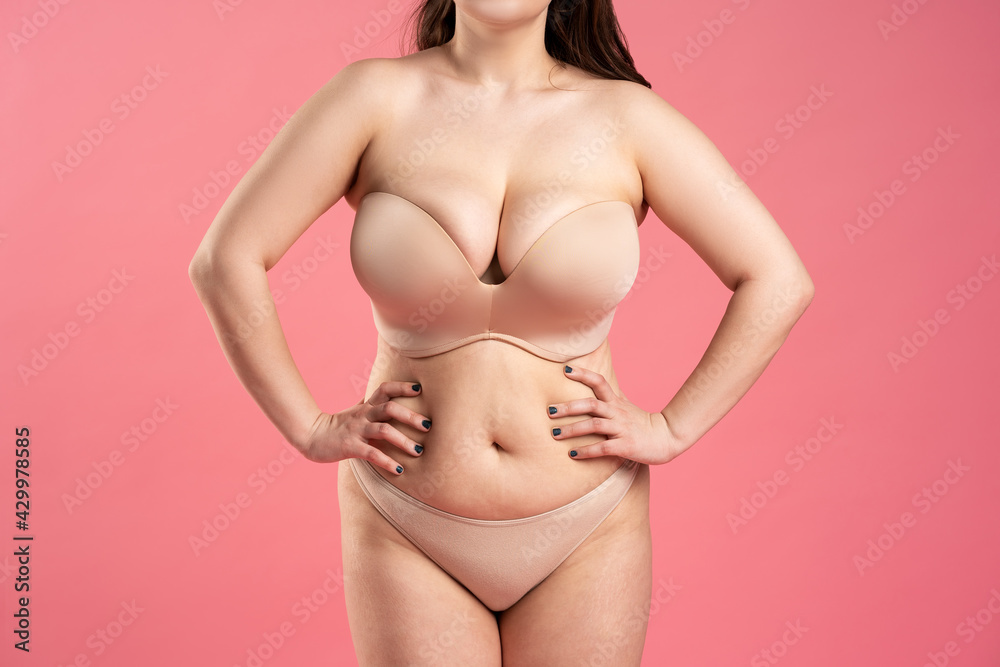 Fat woman with large breasts in a push-up bra on pink background,  overweight female body Stock Photo