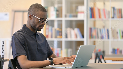 Focused Young African Man Working on Laptop in Library