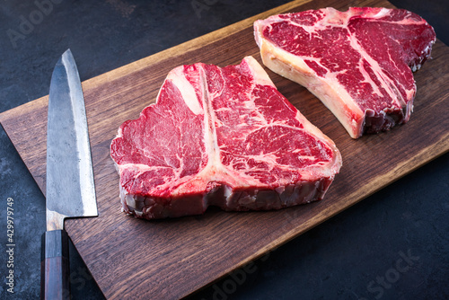Schilderij op canvas Two raw dry aged wagyu porterhouse beef steaks offered as close-up on modern des