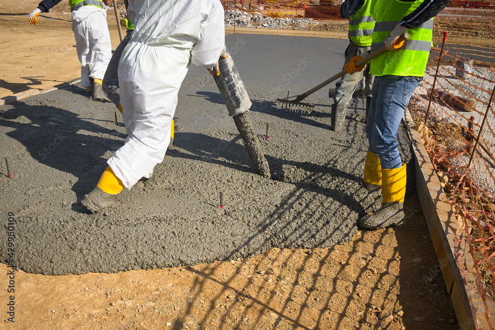 Construction workers dressed in uniform pour a concrete to formwork
