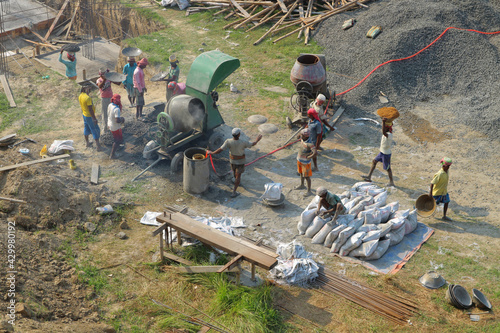 Top view of the Indian construction site. Indian people interfere with concrete, carry gravel and bags of cement. Asian builders are engaged in construction. India, Mayapur, March 16, 2019.