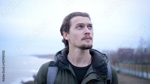 Portrait of young depressed male lonely walks on a winter beach break. 
