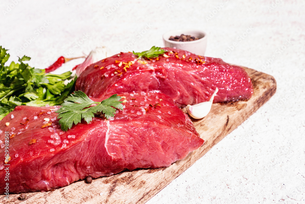 Fototapeta premium Raw beef steaks on a wooden cutting board