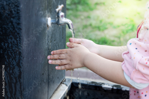 A child washing his hands by the tap. 