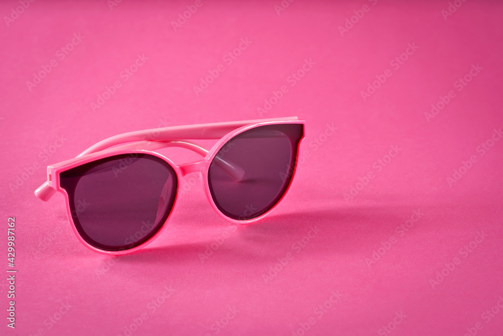 Sunglasses on a pink background. Women's glasses close up. Copy space and place for text near the glasses. Sunglasses on a pink background. Women's glasses close up. Copy space and place for text near the glasses.