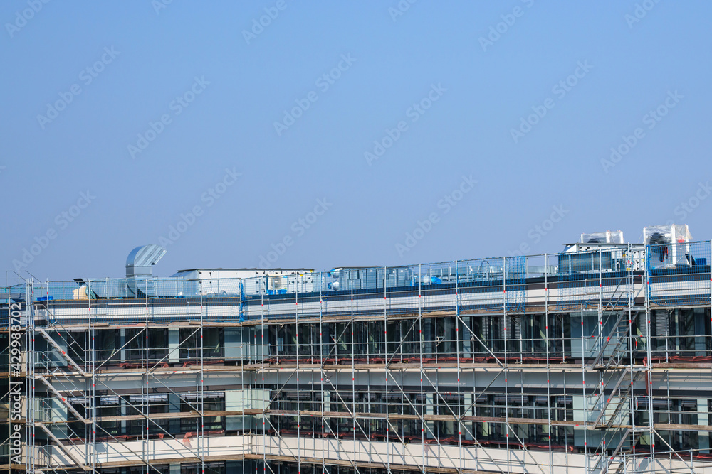 Scaffolding around an unfinished building under a clear sky.