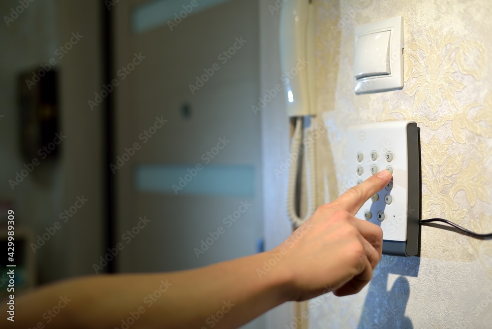 man's hand dials the code from the security system at home on a keypad with numbers from theft and burglary. Surveillance and protection console against rubbery and thief man's hand dials the code from the security system at home on a keypad with numbers from theft and burglary. Surveillance and protection console against rubbery and thief