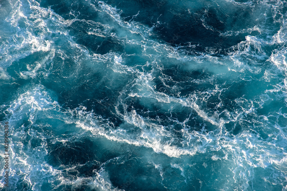 Stormy ocean waves backlit by the light of the setting sun. Transparent. Navy blue. Blue. Background. Pattern.