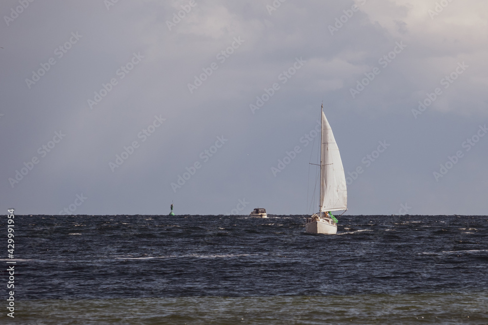 on the sea floats one white sailboat in nice weather